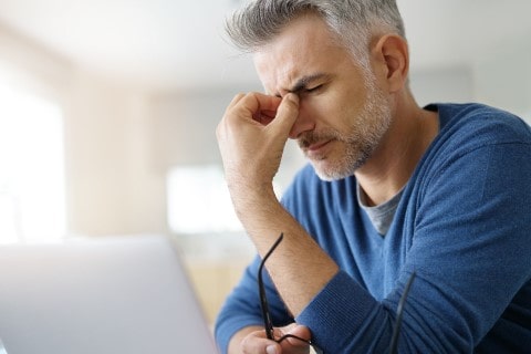 Picture of a Male on a computer dealing with a headache after a car accident