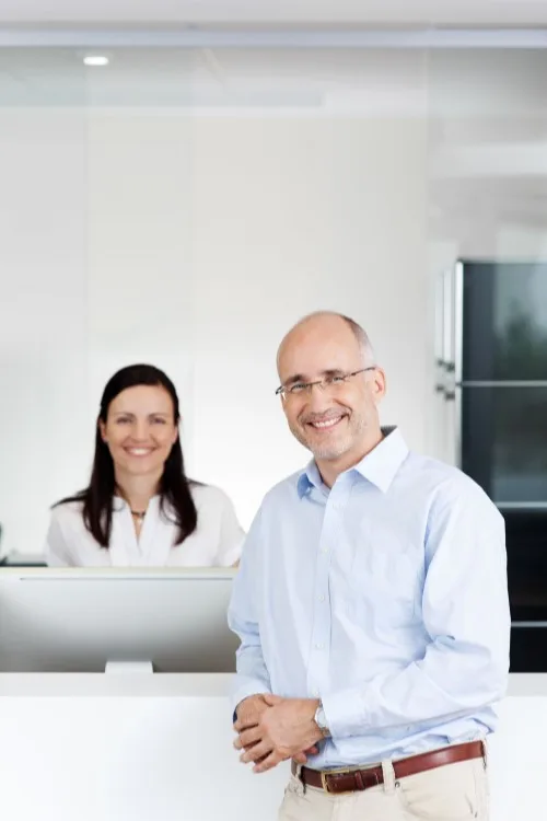 Friendly receptionist at a chiropractic and physical therapy front desk welcoming a car accident patient