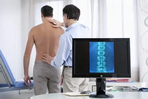 Doctor Examining Patient with Back Pain in Urgent Care Like Office Patient with lower back pain seeing a chiropractor instead of urgent care